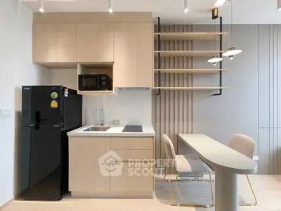 Modern kitchen with sleek cabinetry, compact dining area, and integrated appliances in a stylish apartment.