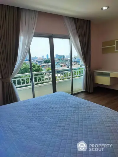 Spacious bedroom with balcony offering stunning city view and natural light