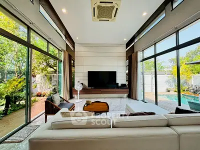 Luxurious living room with floor-to-ceiling windows and pool view, featuring modern furniture and high ceilings.
