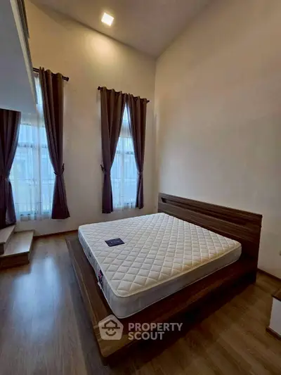 Spacious bedroom with high ceiling and large windows for natural light
