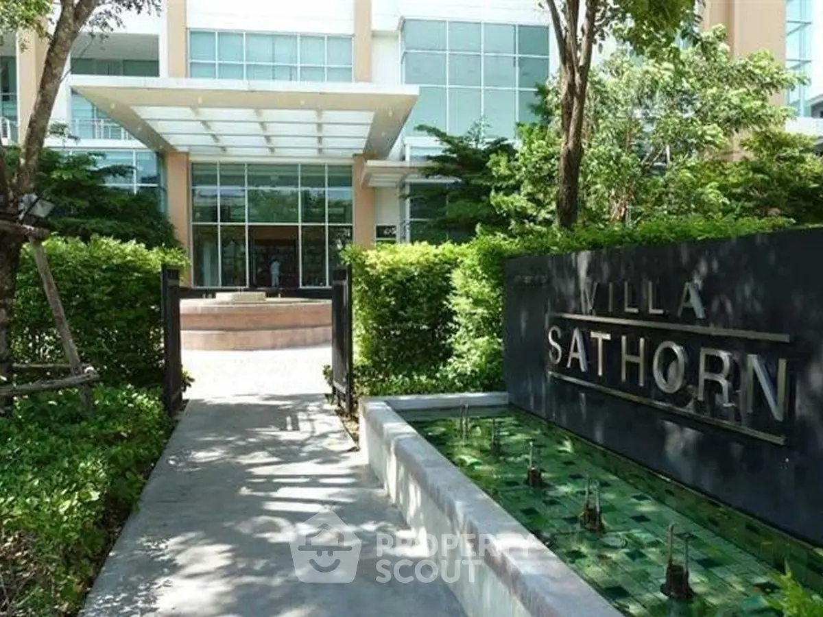 Elegant entrance of Villa Sathorn with lush greenery and modern architecture.