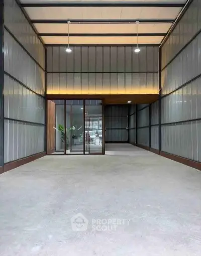 Spacious industrial-style interior with high ceilings and glass doors, ideal for versatile use.
