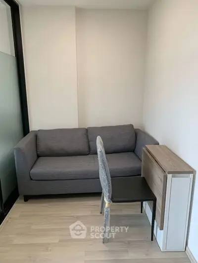 Cozy small living room with modern gray sofa and compact dining setup.