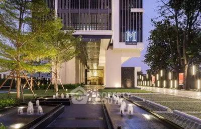 Luxurious modern building entrance with elegant water features and lush landscaping.