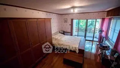 Spacious bedroom with wooden flooring and balcony access, offering serene views and natural light.