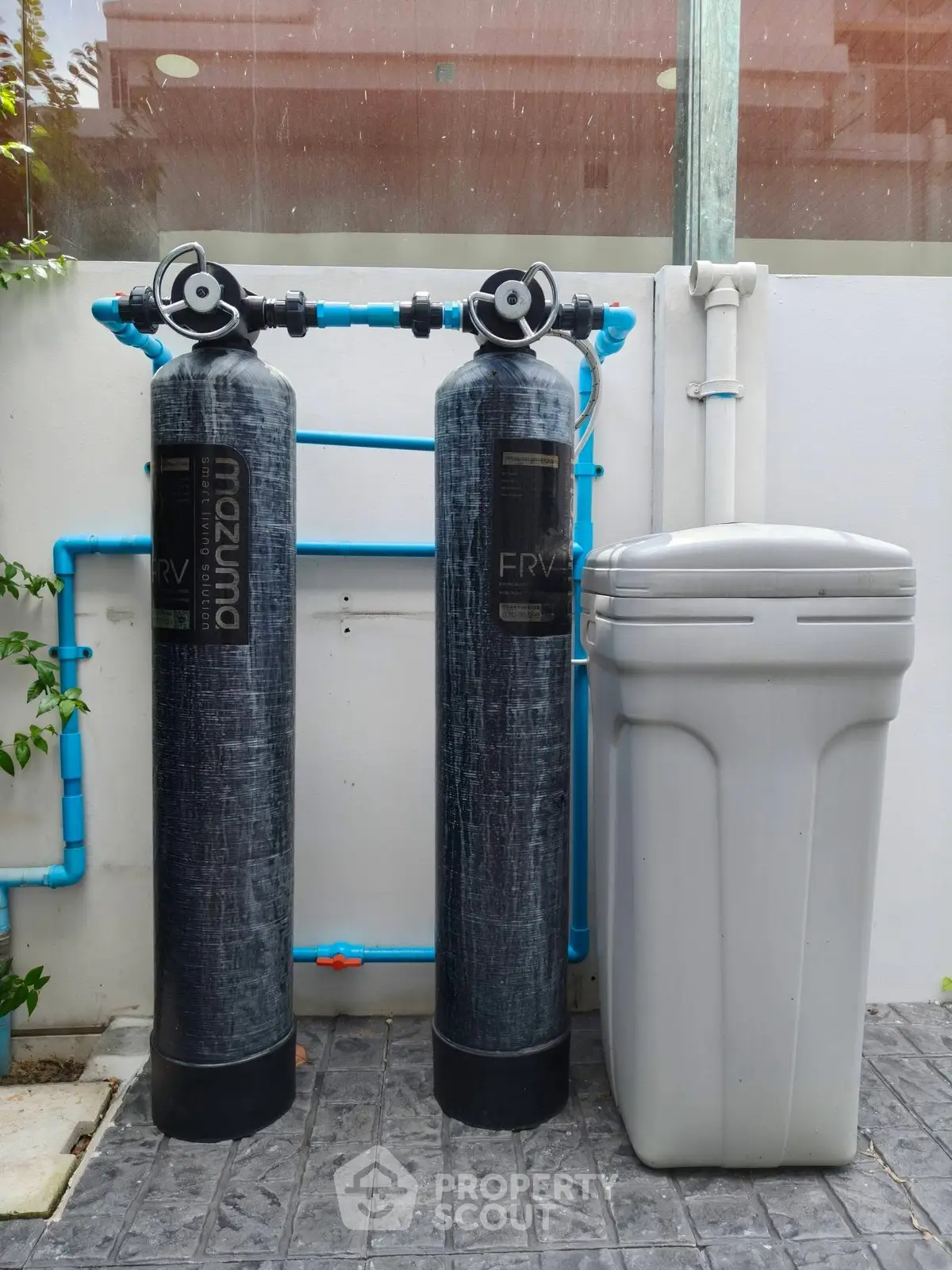 Outdoor water filtration system with dual tanks and waste bin in modern residential setting.
