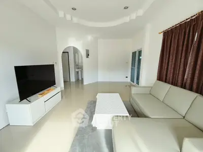 Spacious living room with modern furniture and large TV, perfect for relaxation.