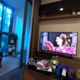 Modern living room with large TV and balcony view, perfect for relaxation and entertainment.