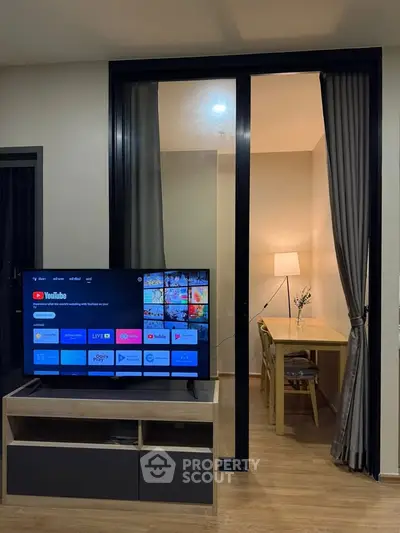 Modern living room with TV and cozy study area, featuring elegant wooden flooring and stylish decor.