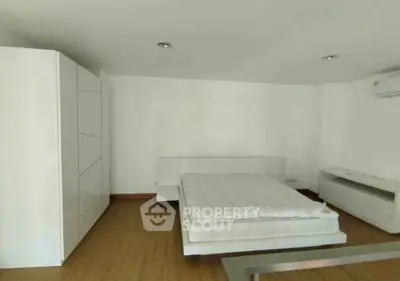 Spacious minimalist bedroom with modern white furniture and wooden flooring