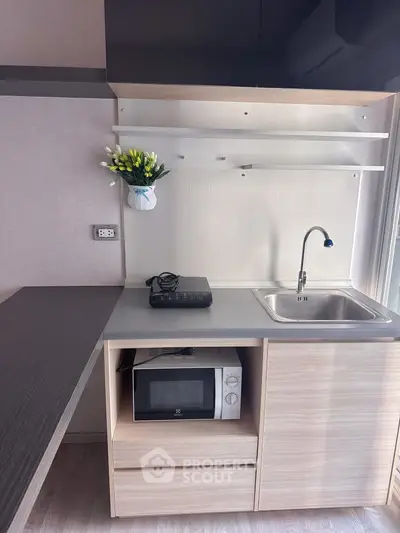 Modern compact kitchen with microwave and induction stove, ideal for small apartments.