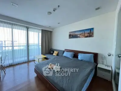 Spacious bedroom with large windows and modern decor, featuring a cozy bed and stylish furnishings.