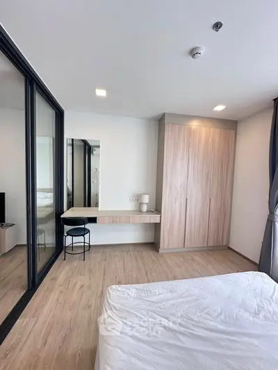 Modern bedroom with wooden flooring, built-in wardrobe, and sleek glass partition.