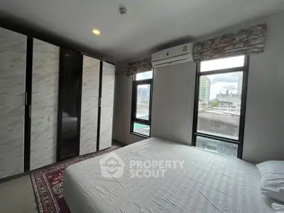 Modern bedroom with large windows and built-in wardrobe in urban apartment