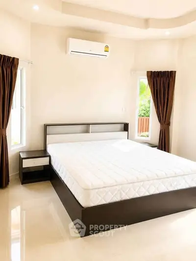 Spacious bedroom with modern design, featuring a large bed and natural light from two windows.