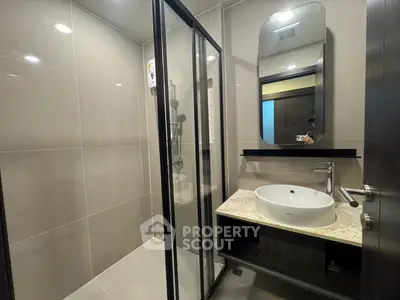 Modern bathroom with sleek shower and stylish vanity in contemporary apartment.