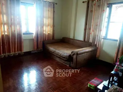 Spacious living room with wooden flooring and cozy sofa, perfect for relaxation.