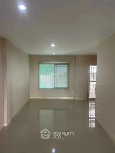 Spacious empty room with glossy tiled floor and large window, perfect for customization.