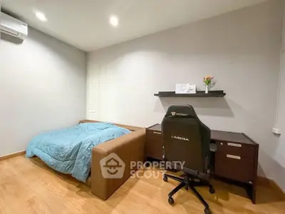 Cozy bedroom with modern desk and comfortable chair, ideal for work and relaxation.