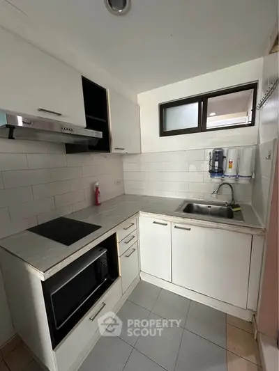 Compact kitchen with modern appliances and sleek cabinetry in a cozy apartment.