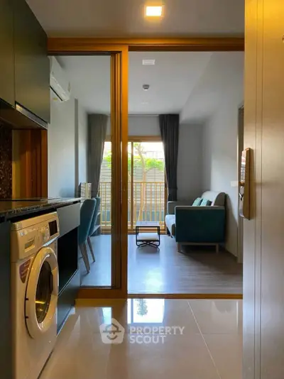 Modern apartment with open layout, featuring a cozy living room and kitchen with washing machine.