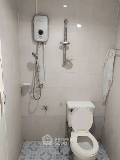 Compact bathroom with shower and toilet, featuring a water heater for convenience.