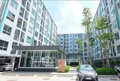 Modern apartment complex with parking and lush greenery, showcasing contemporary urban living.