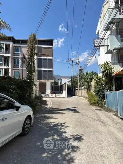 Modern residential building exterior with clear blue sky and street view.
