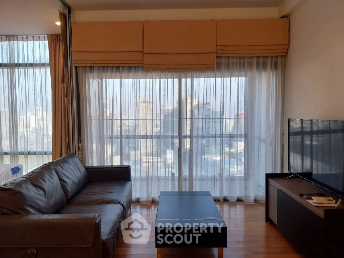 Spacious living room with large windows and modern furniture offering city views