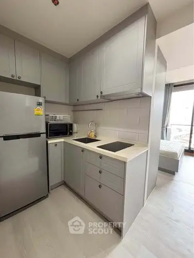 Modern compact kitchen with sleek cabinetry and built-in appliances in a stylish apartment.