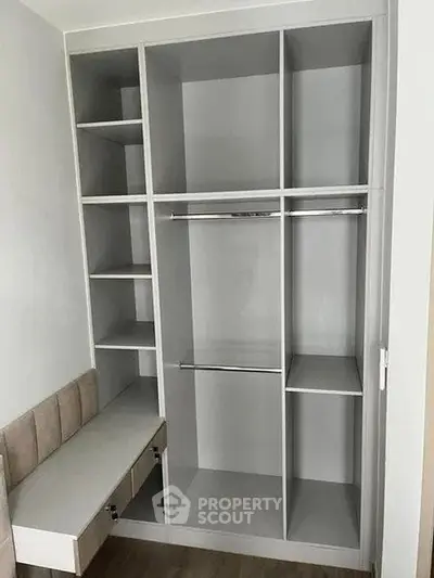 Spacious built-in wardrobe with multiple shelves and hanging rods in modern apartment.
