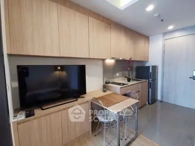 Modern kitchen with sleek cabinetry, compact dining area, and integrated appliances in a stylish apartment.