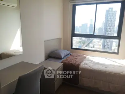 Cozy bedroom with city view, featuring a single bed, desk, and large window for natural light.