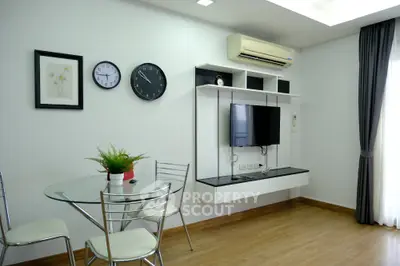 Modern living room with wall-mounted TV, glass dining table, and air conditioning.