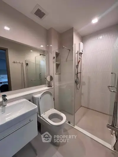 Modern bathroom with sleek fixtures and glass shower enclosure in a contemporary apartment.