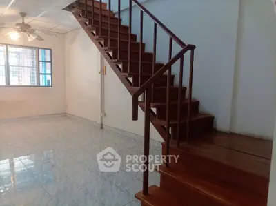 Spacious living room with wooden staircase and ceiling fan, perfect for modern living.