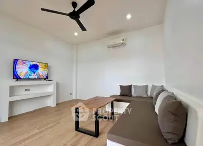 Modern minimalist living room with sleek furniture and wall-mounted TV, perfect for relaxation.