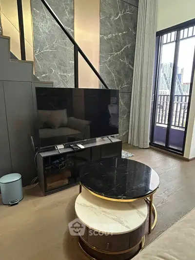 Modern living room with stylish decor and large TV, featuring a balcony with city view.