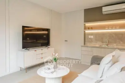 Modern living room with sleek TV unit and stylish open kitchen layout.