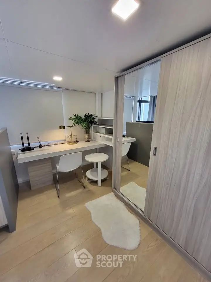 Modern study room with sleek desk, chairs, and mirrored wardrobe in stylish apartment.