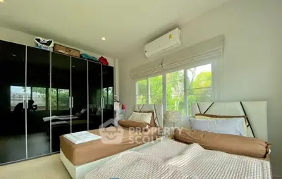 Spacious bedroom with twin beds, large wardrobe, and natural light from window.