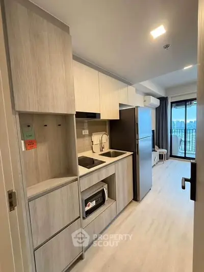 Modern kitchen with sleek cabinetry and open layout leading to a bright living area with city view.