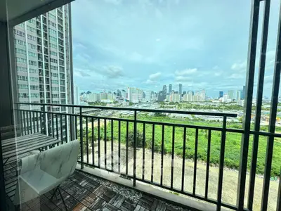 Stunning cityscape view from a modern balcony with seating area, perfect for relaxation.