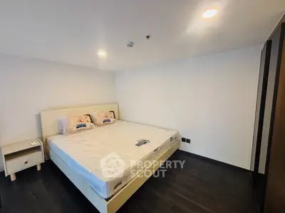 Spacious bedroom with modern design and cozy lighting, featuring a large bed and sleek dark flooring.