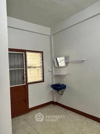 Minimalist bathroom with blue sink and small window, perfect for compact living spaces.