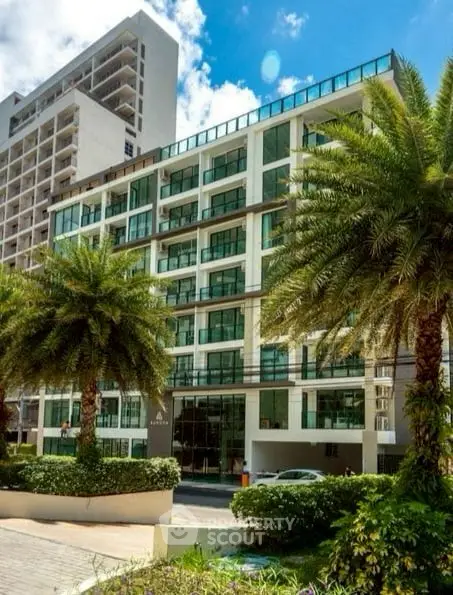 Modern urban building with lush palm trees and sleek glass facade.