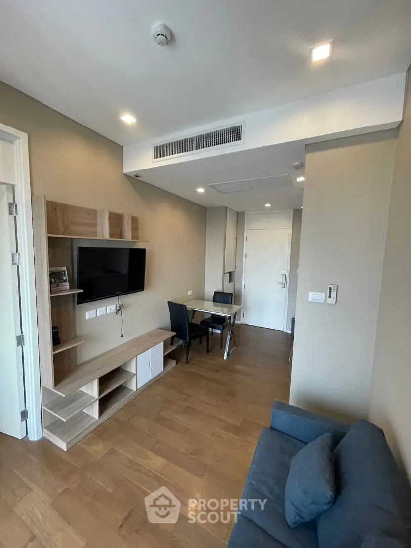 Modern living room with wooden flooring and wall-mounted TV in a cozy apartment.