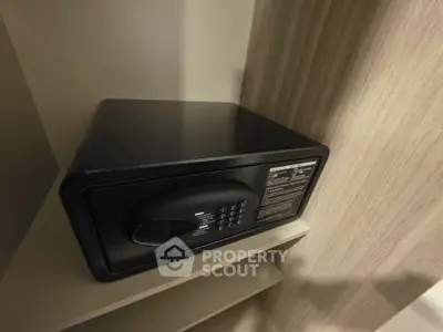 Secure black safe in modern storage space, ideal for valuables protection in real estate property.