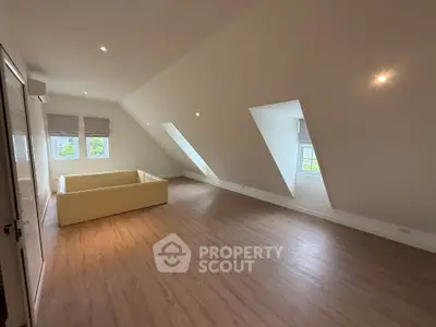 Spacious attic living room with sloped ceiling and large windows