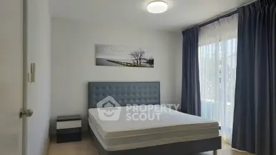 Spacious bedroom with modern decor and large window for natural light